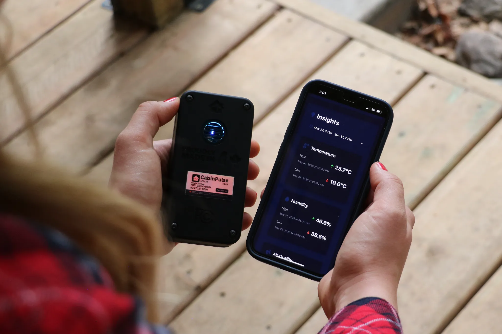 The CabinPulse device and a phone showing its readings, held in someone's hands on a cabin deck